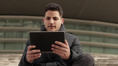 Focused-brunet-programmer-with-bristle-working-with-tablet-outdoor